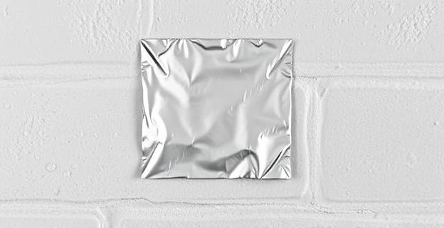 Una pared con un trozo de papel de aluminio pegado, mostrando gotas de condensación en su superficie